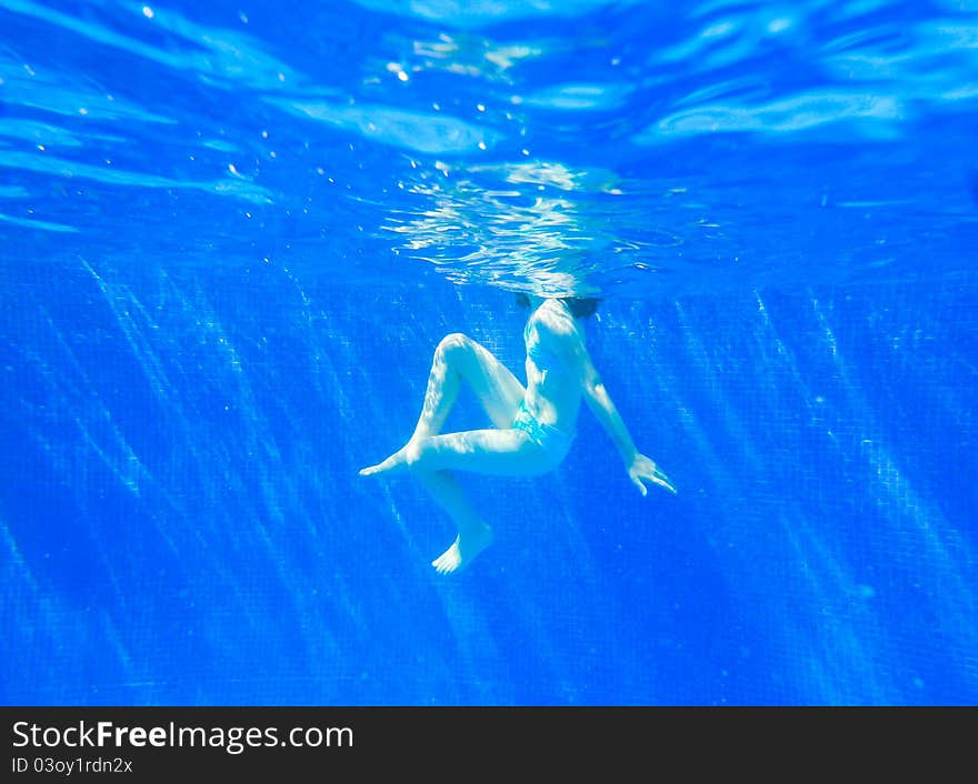 A young boy swimming in a clear pool. A young boy swimming in a clear pool