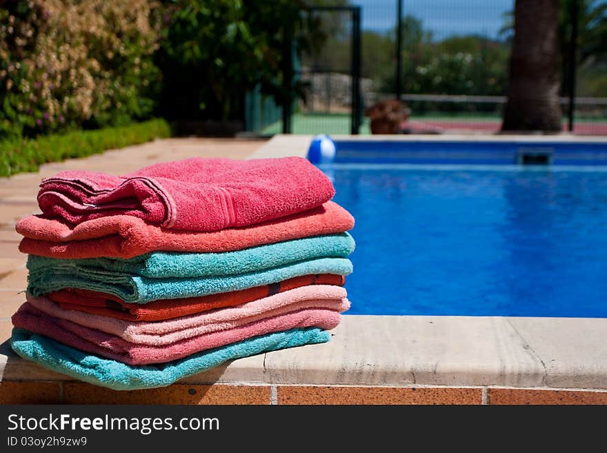 A pile of towels beside a beautiful pool. A pile of towels beside a beautiful pool