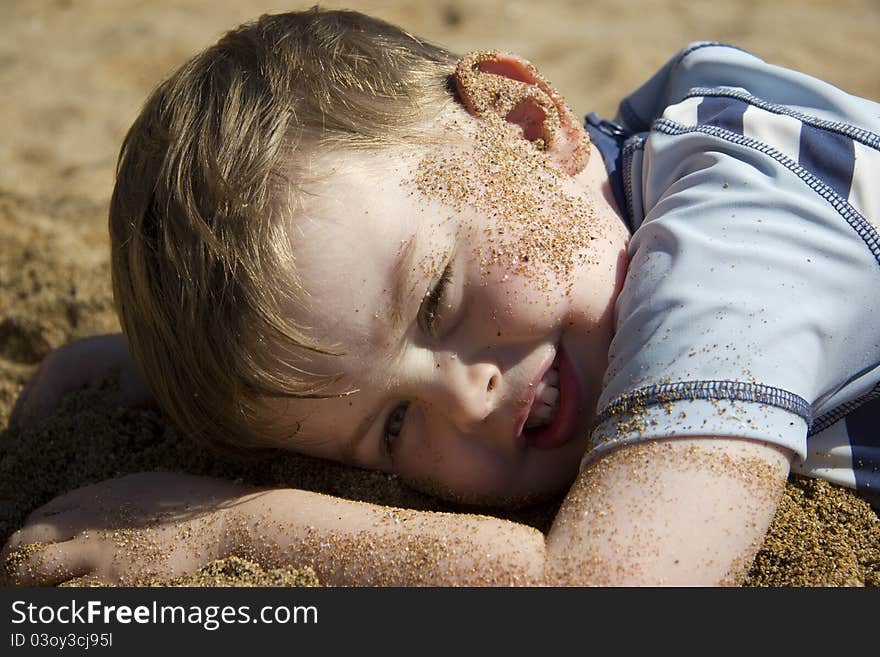 Happy boy lying on beach