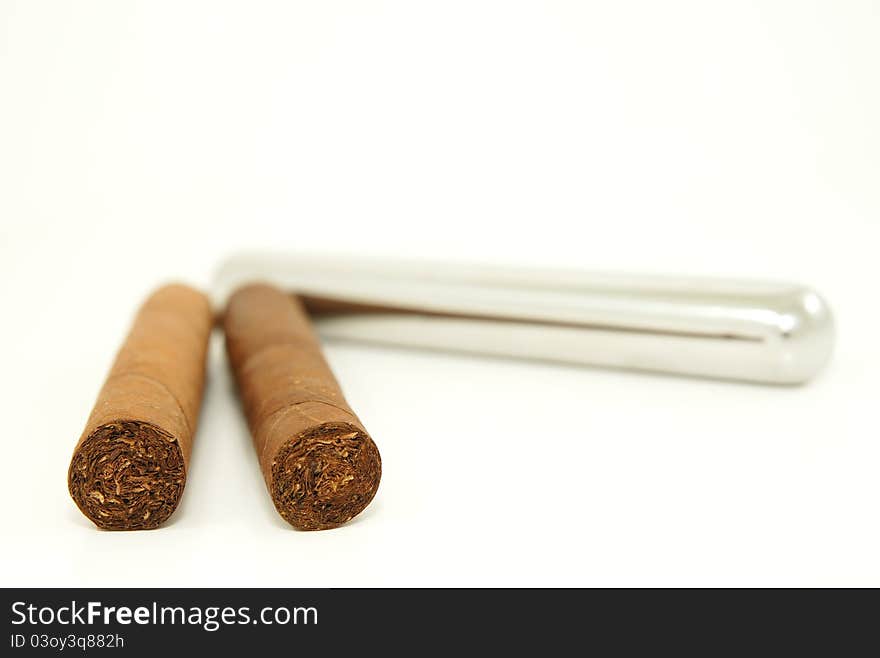 Close-up of two cigars and a stainless steel tube container. Close-up of two cigars and a stainless steel tube container