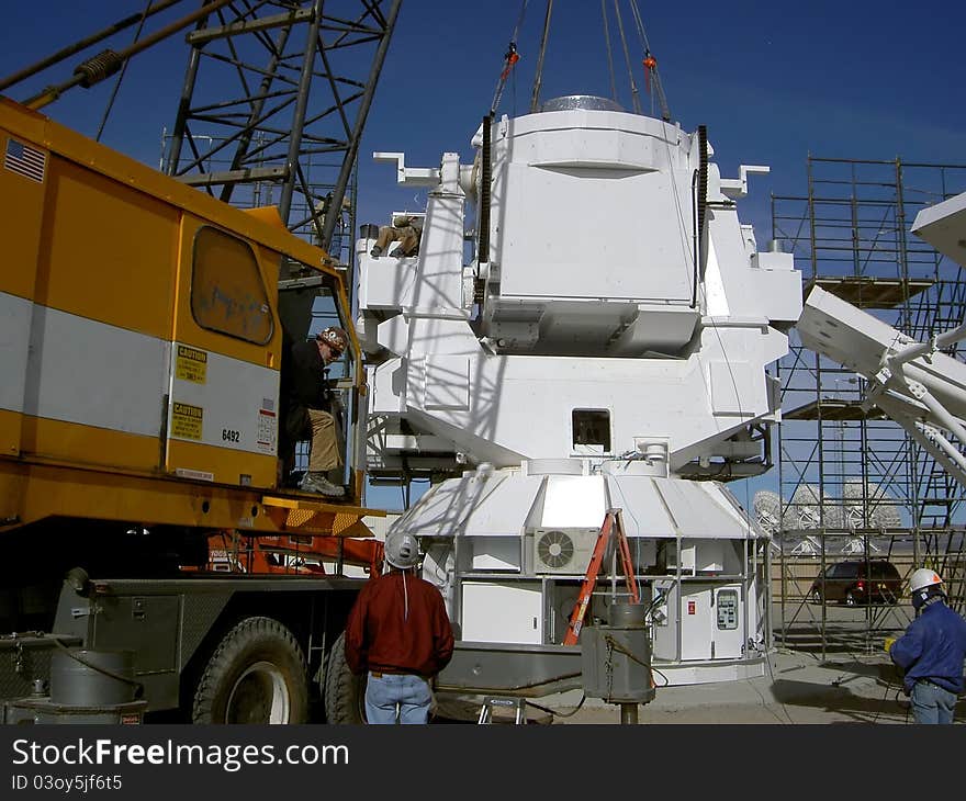 At the very large array located in new mexico, usa, a crane sets the base for a new radio astronomy observatory;. At the very large array located in new mexico, usa, a crane sets the base for a new radio astronomy observatory;