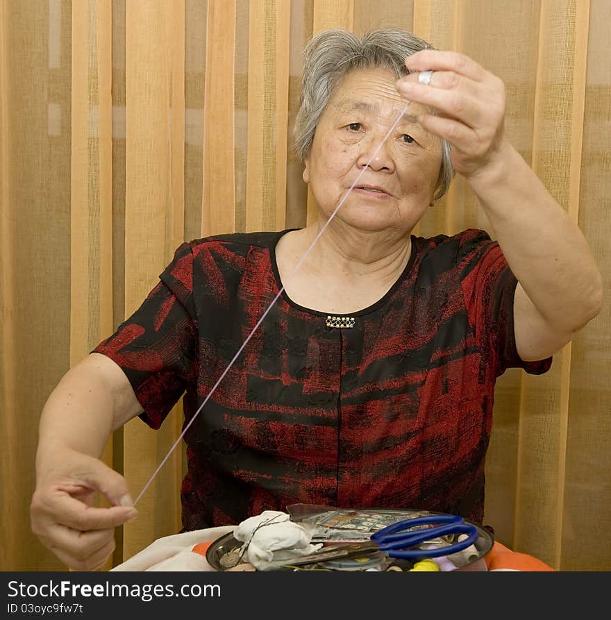 A grandma is sewing at home. A grandma is sewing at home