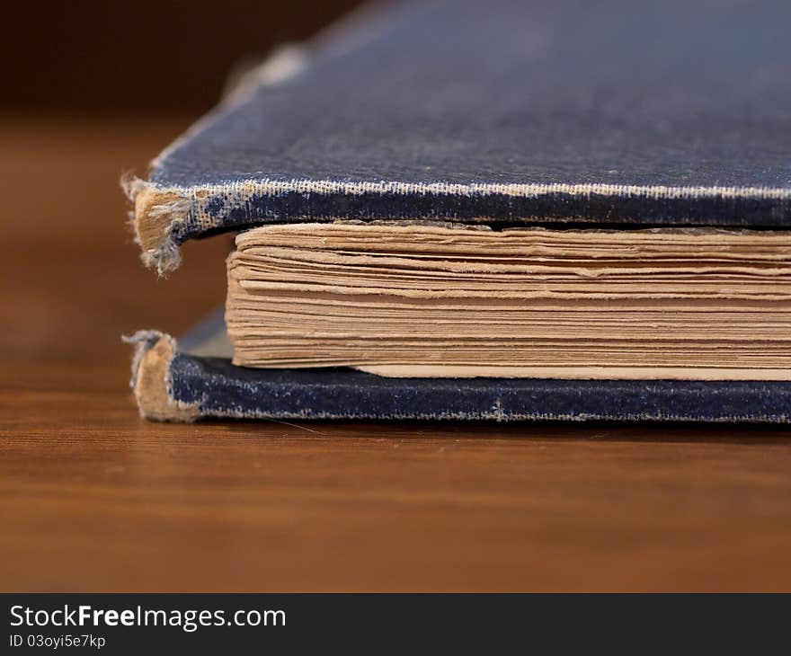 The dog eared corner of an old book on a wooden surface. The dog eared corner of an old book on a wooden surface.