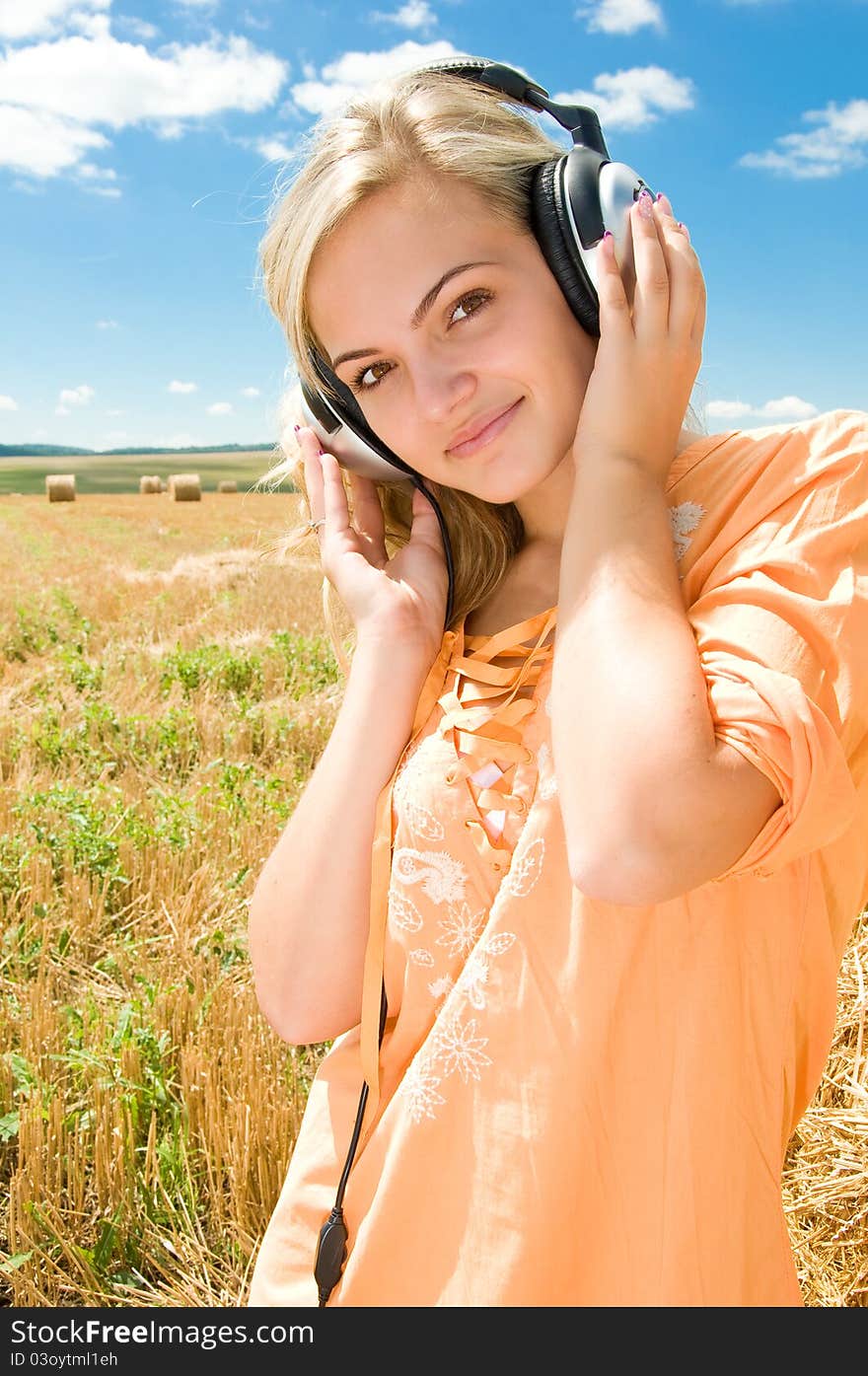 Girl at a stack of straw listening to music