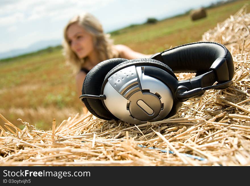 Girl at a stack of straw listening to music