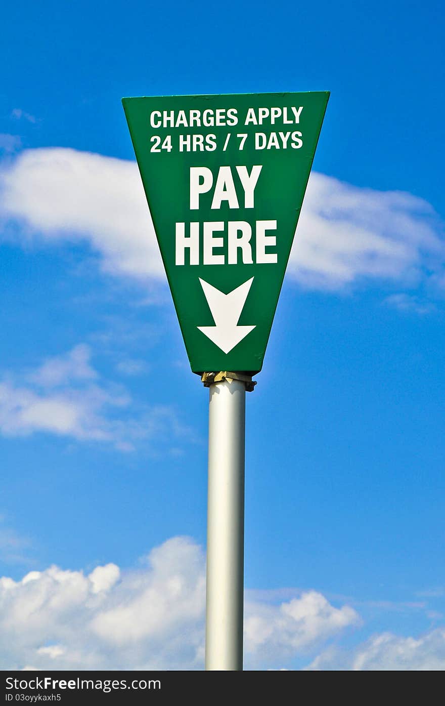 Green pay here sign with blue sky in background