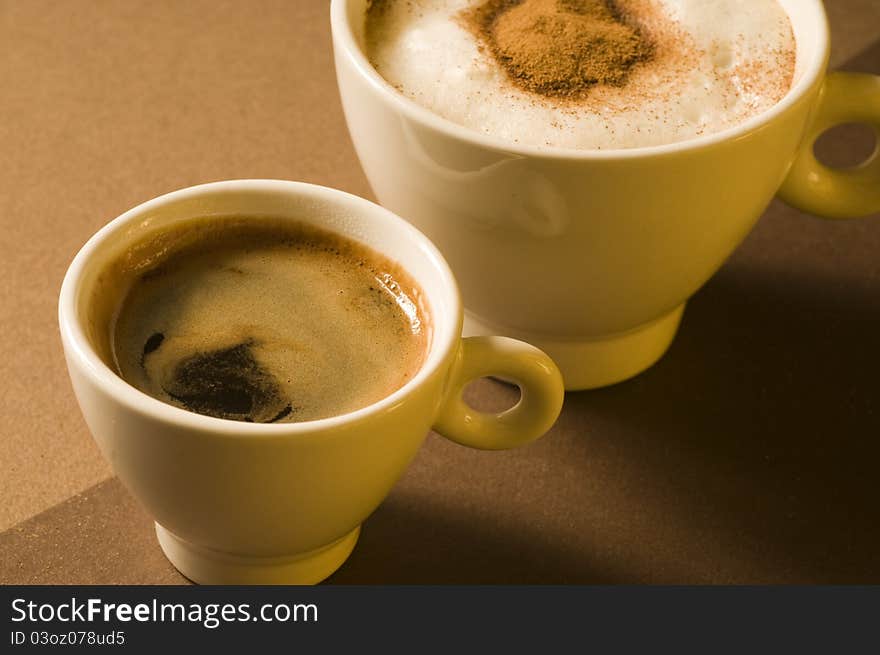 Two coffee cups with hot espresso and cappuccino over brown background. Two coffee cups with hot espresso and cappuccino over brown background