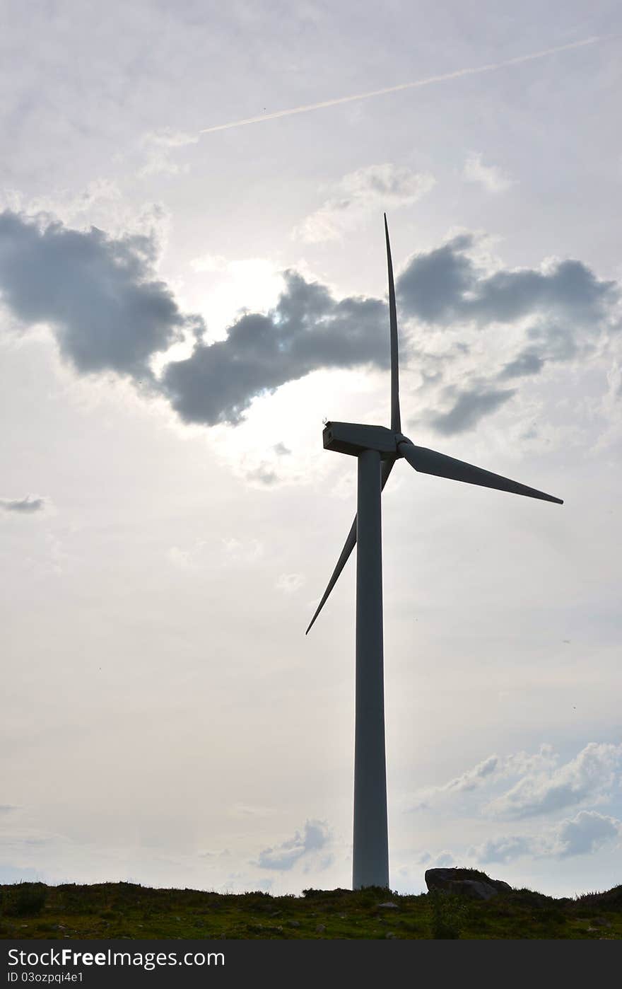 Wind turbine against the light with dramatic clouds