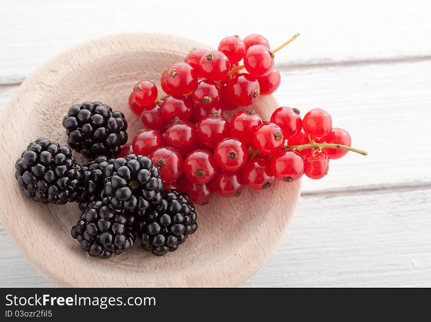 Blackberries and currants on a wooden white table