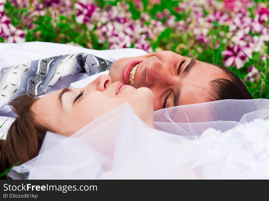 Happy bride and groom lying on a green grass