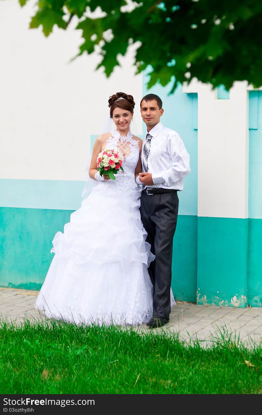 Happy bride and groom near the church wall