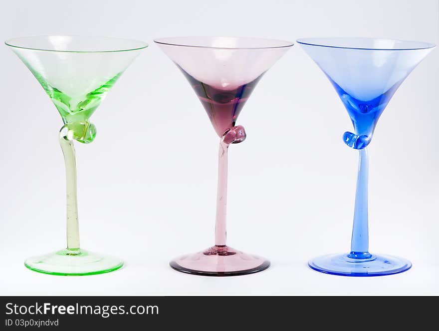 A row of three colorful cocktail glasses, green, red, blue.