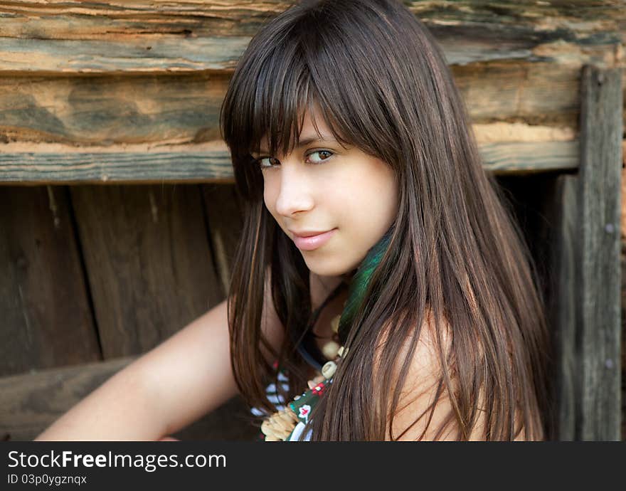 A portrait of a young woman, leaning against a wooden wall and looking at the viewer flirtatiously. A portrait of a young woman, leaning against a wooden wall and looking at the viewer flirtatiously