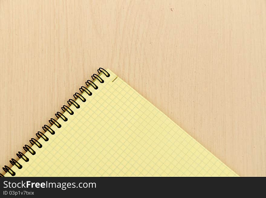 Yellow note book on wooden table background