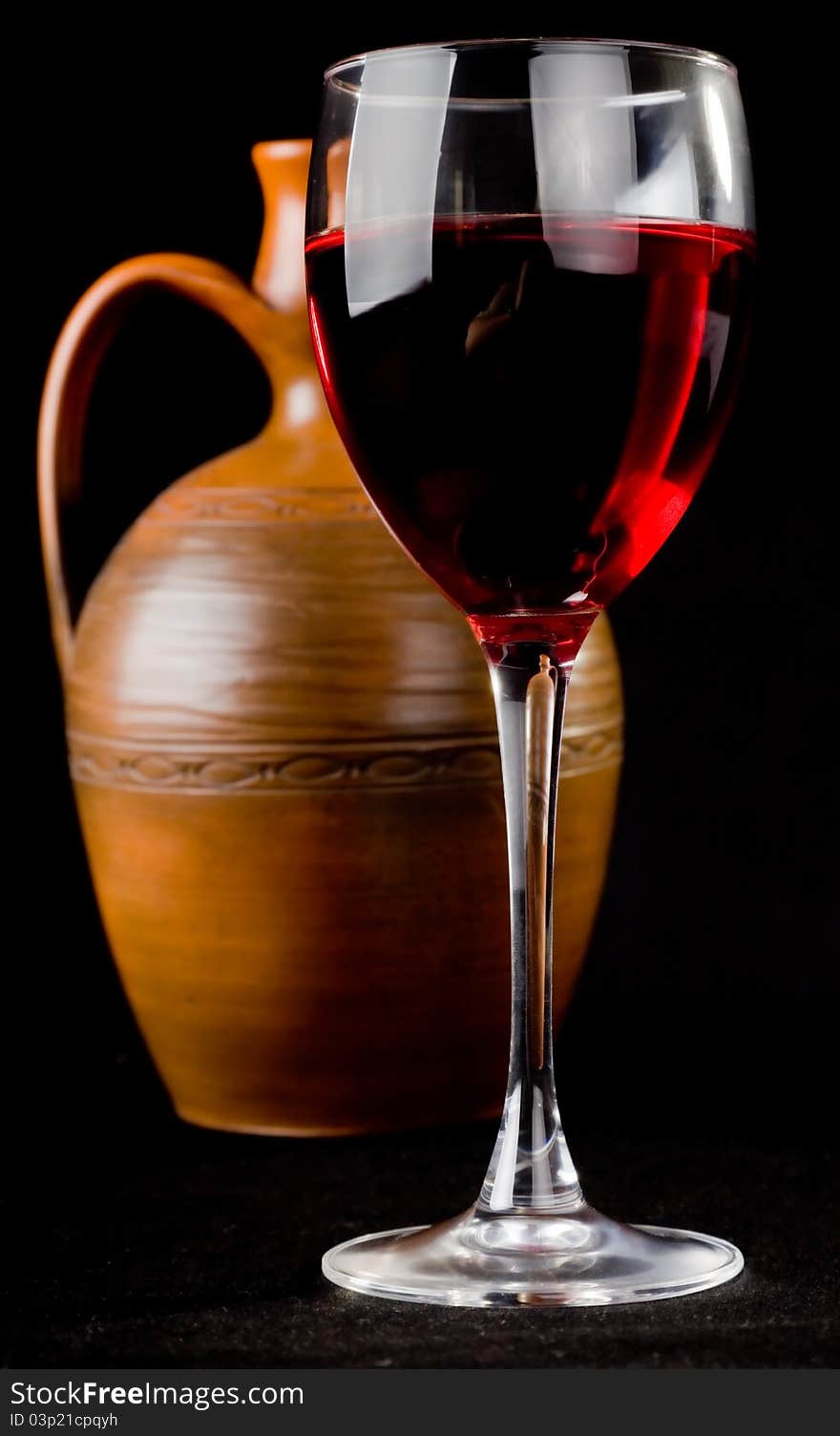 Pitcher and a glass of red liquid on a black background