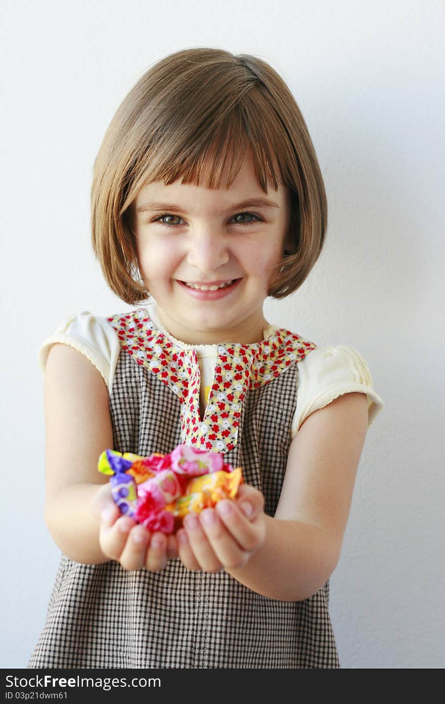 Little girl holding candies looking at the camera smiling