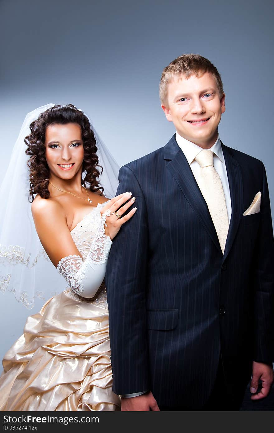 Studio portrait of young elegant enamoured just married bride and groom and embracing on grey background. Studio portrait of young elegant enamoured just married bride and groom and embracing on grey background