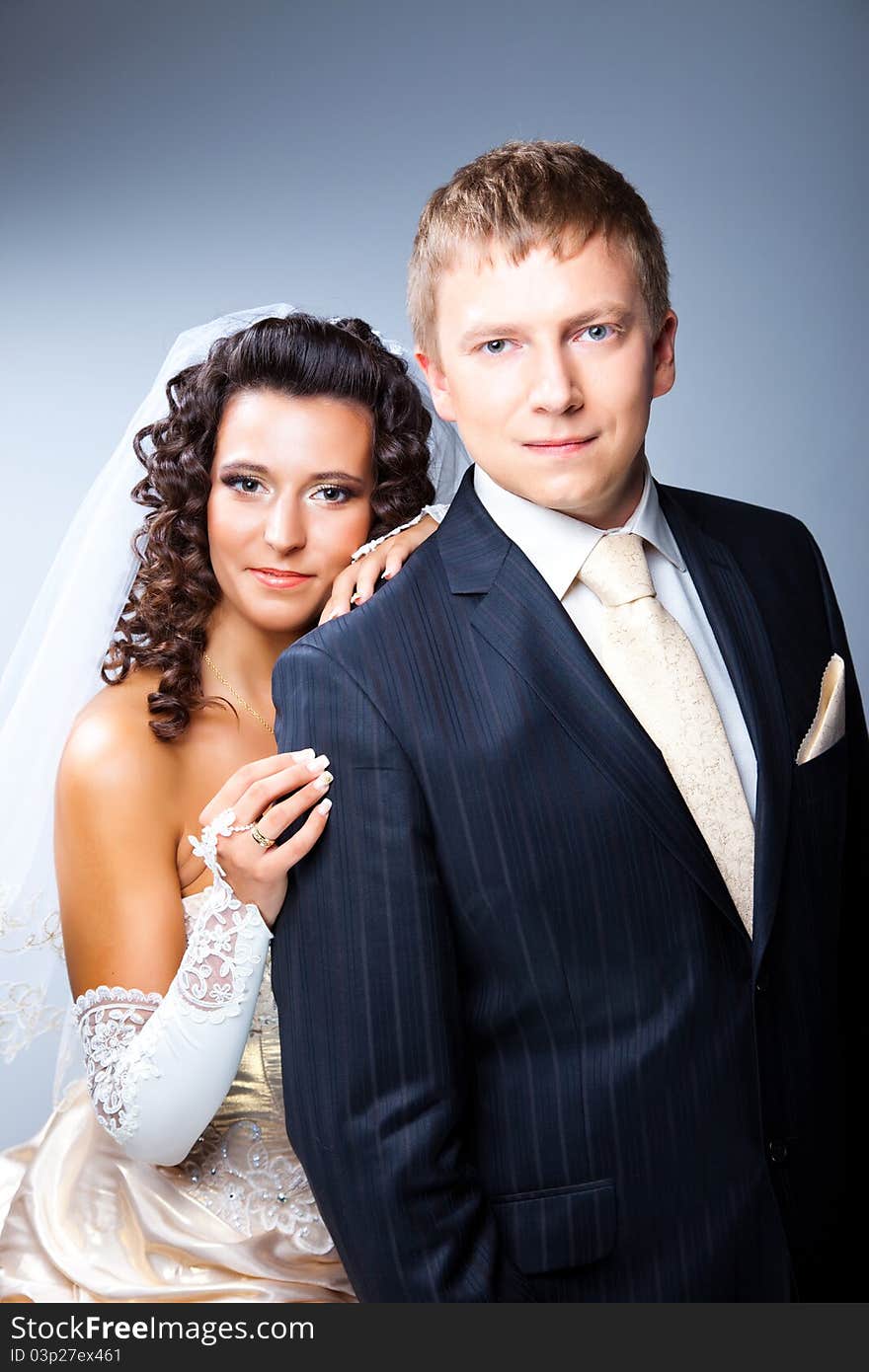 Studio portrait of young elegant enamoured just married bride and groom and embracing on grey background. Studio portrait of young elegant enamoured just married bride and groom and embracing on grey background