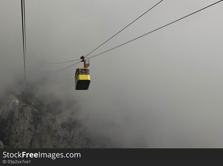 The cable car in Crimea Ai-Petri on a background of mountains covered with clouds. The cable car in Crimea Ai-Petri on a background of mountains covered with clouds