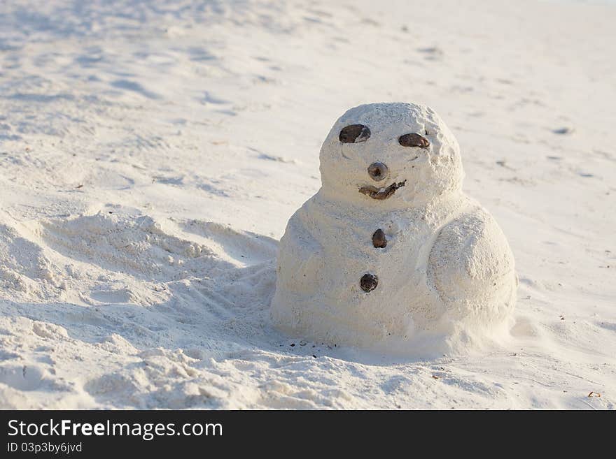 Sandman. Doll from sand on white beach. Snowman