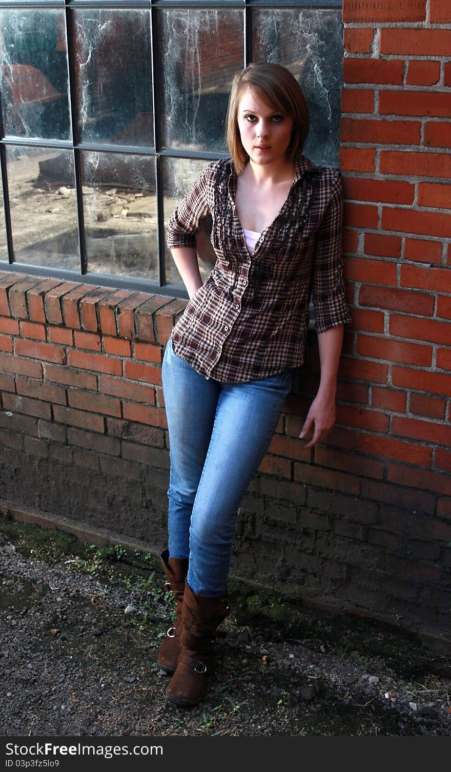 A beautiful young woman standing by a brick wall. A beautiful young woman standing by a brick wall