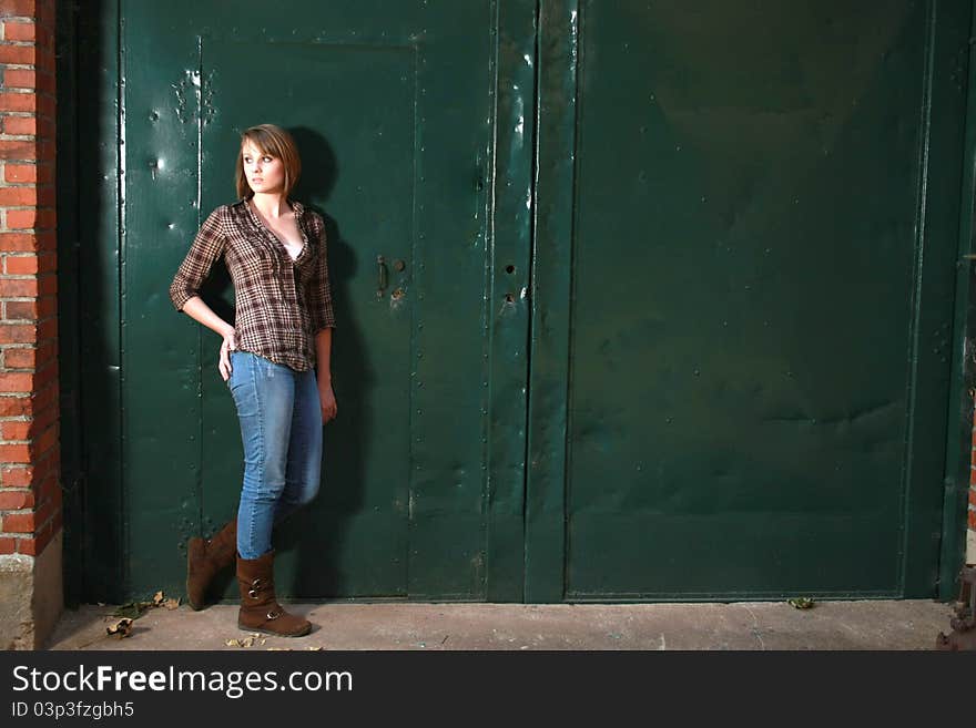 A young woman standing by s apir of green doors. A young woman standing by s apir of green doors