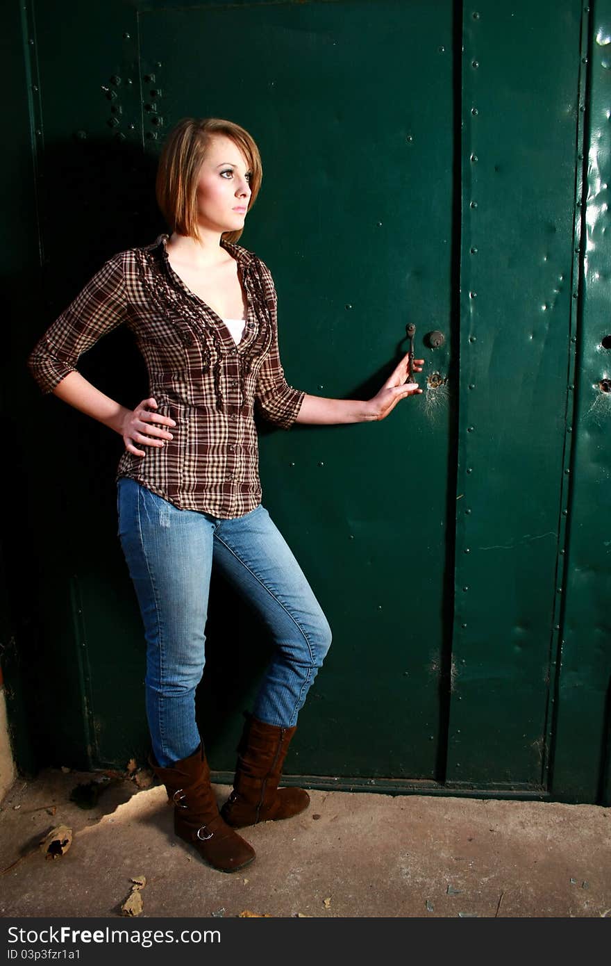 A beautiful young woman standing by a green door. A beautiful young woman standing by a green door