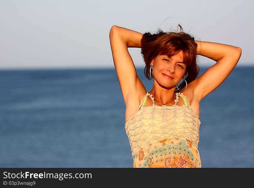 Attractive woman holding her hair on a sea (ocean) background outdoor