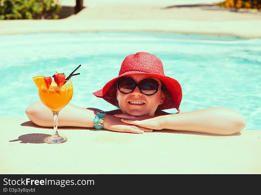 Beautiful woman relaxing in swimming pool with cocktail and smiling. Beautiful woman relaxing in swimming pool with cocktail and smiling