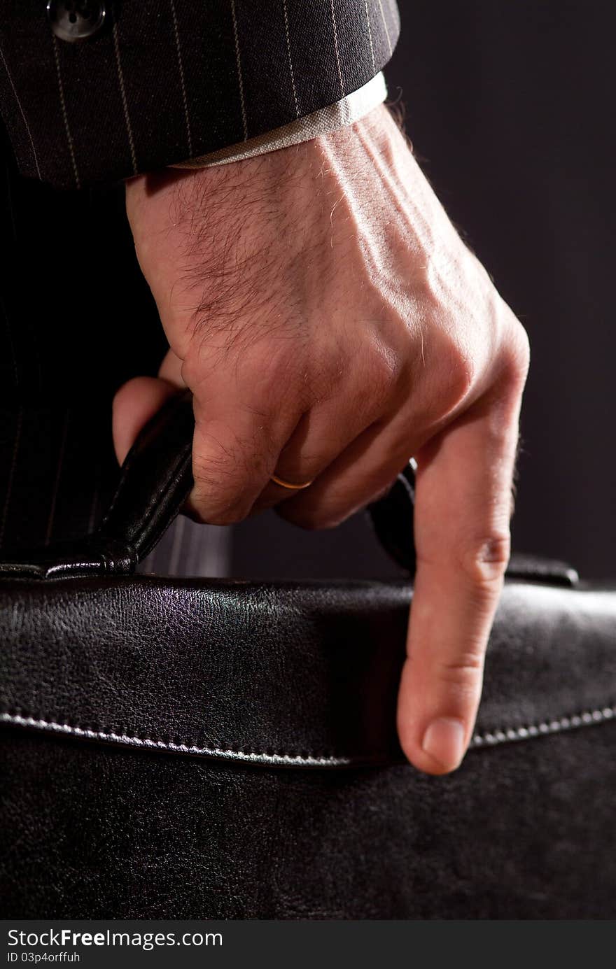 The hands of a businessman carrying a briefcase