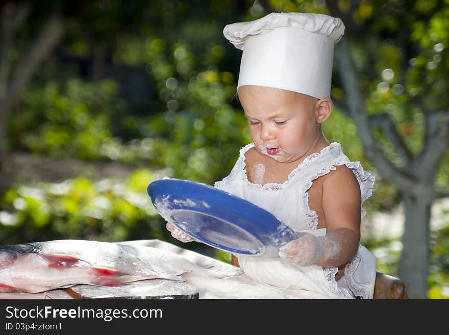 Cute little baby in cook hat holding a blue plate. Cute little baby in cook hat holding a blue plate.