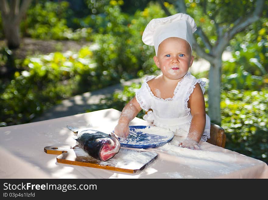 Cute little baby in chef hat ready to cook fish. Cute little baby in chef hat ready to cook fish.