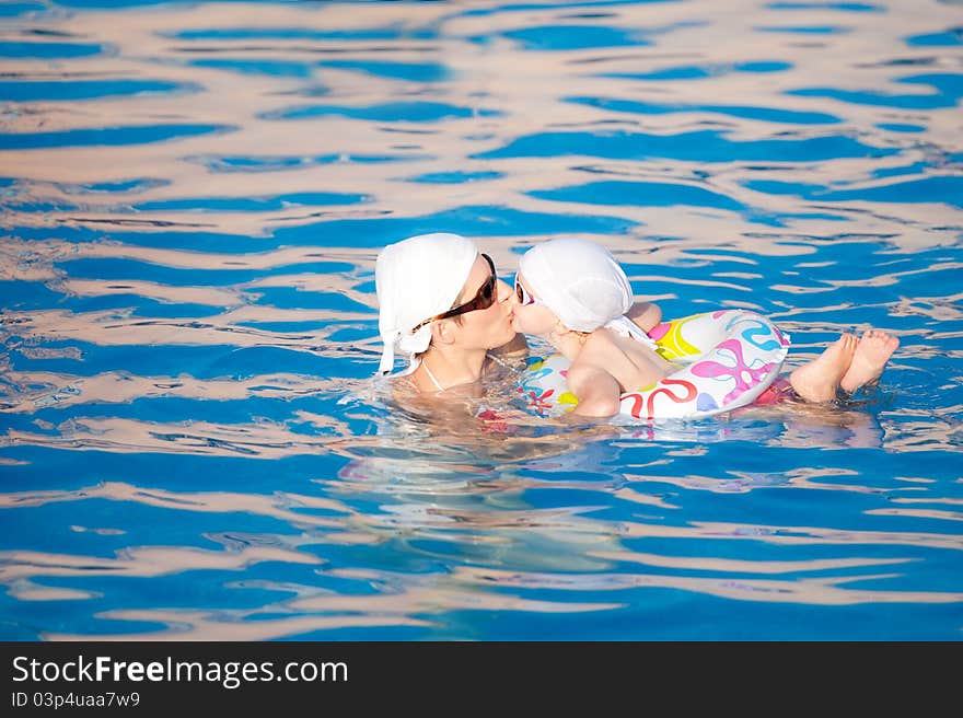 Baby with mother are swimming in pool