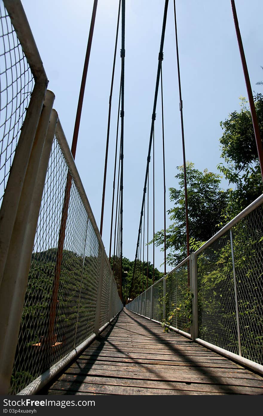 Picture of a cable suspension bridge located on the top of a moutain with trees surrounding