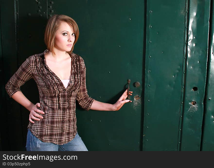 A young woman standing by a green door. A young woman standing by a green door