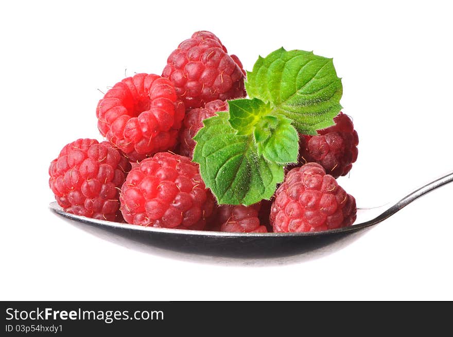 Raspberryes and twig of mint on a spoon, isolated on white