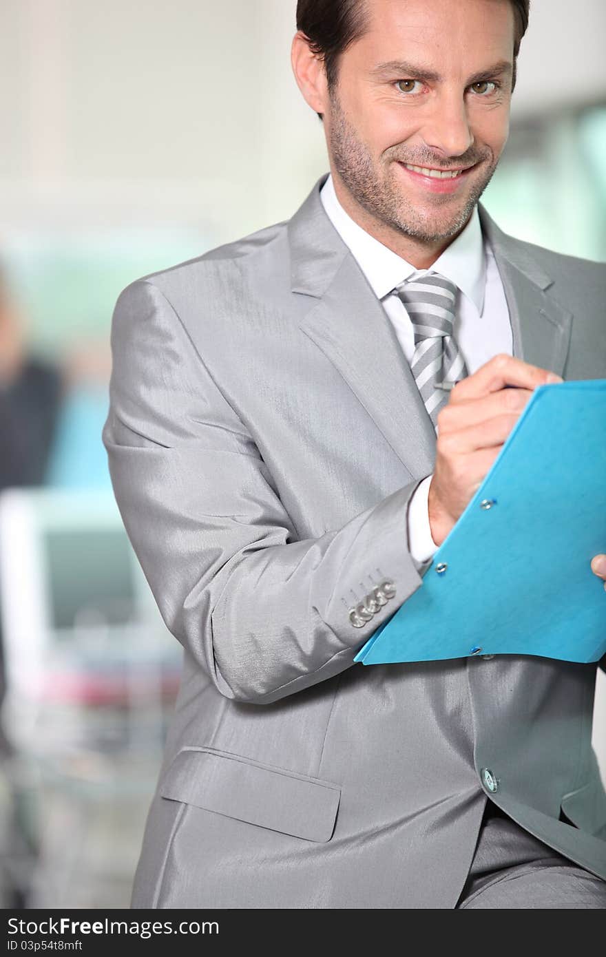 Portrait of businessman writing notes in a blue folder. Portrait of businessman writing notes in a blue folder