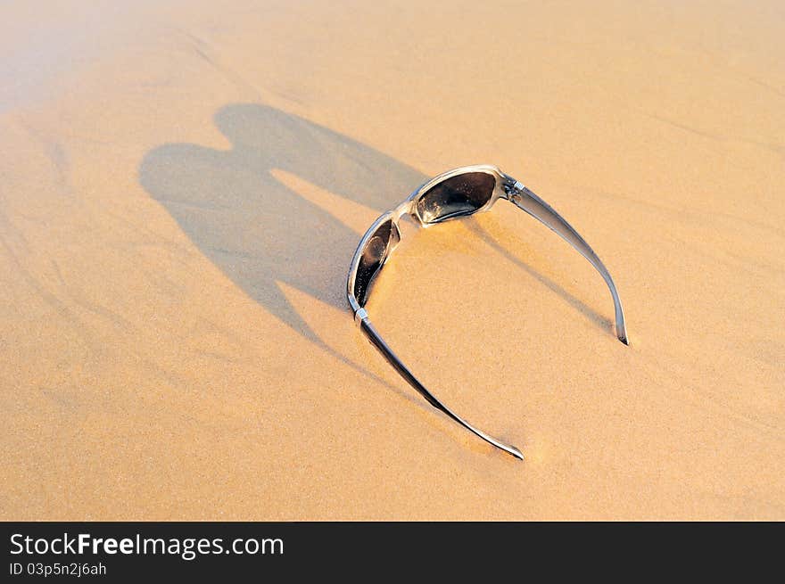 Sunglasses on the sandy beach at the sea