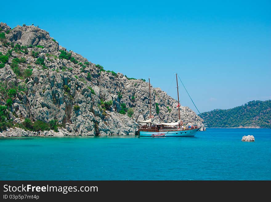 The small white boat is in the beautiful blue sea with mountains and on background blue sky of the Turkey. The small white boat is in the beautiful blue sea with mountains and on background blue sky of the Turkey