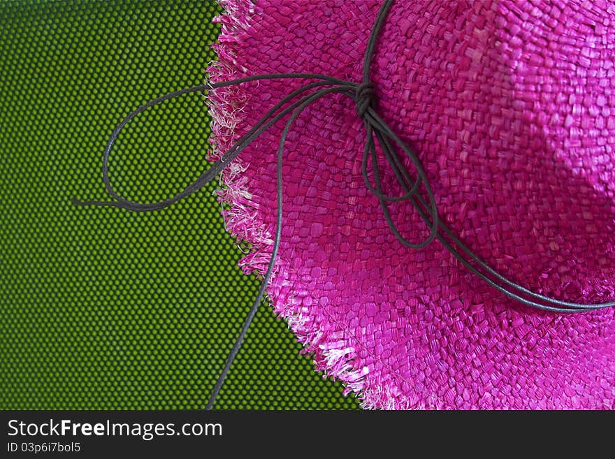 Pink straw hat with string, on green background. Pink straw hat with string, on green background.