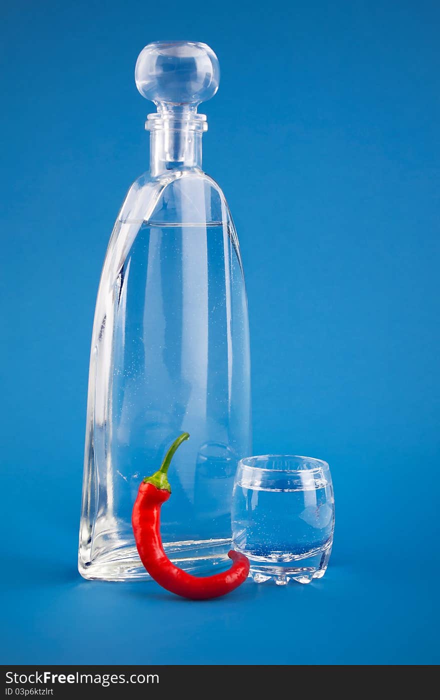 Bottle vodka hot cayenne chili on blue background. Bottle vodka hot cayenne chili on blue background