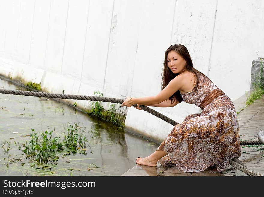 Beautiful girl pulling a rope near river