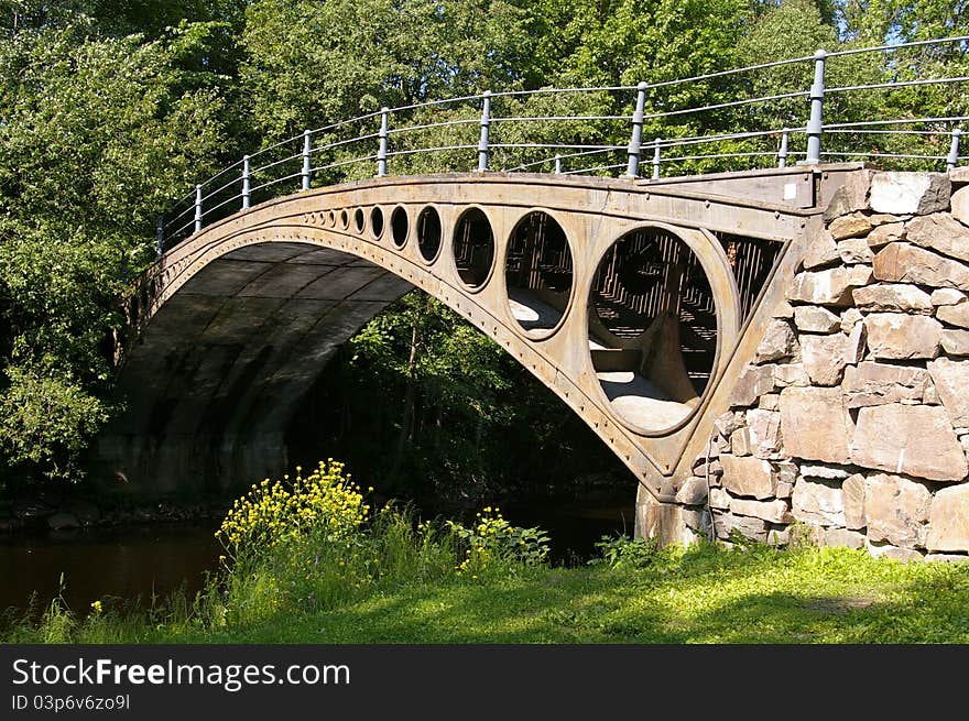 Small classical design metal bridge over a river in the woods. Small classical design metal bridge over a river in the woods