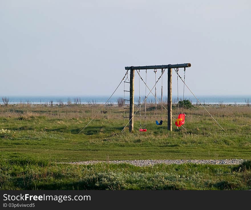 Cute playground with colorful swings on the beach by the ocean. Cute playground with colorful swings on the beach by the ocean