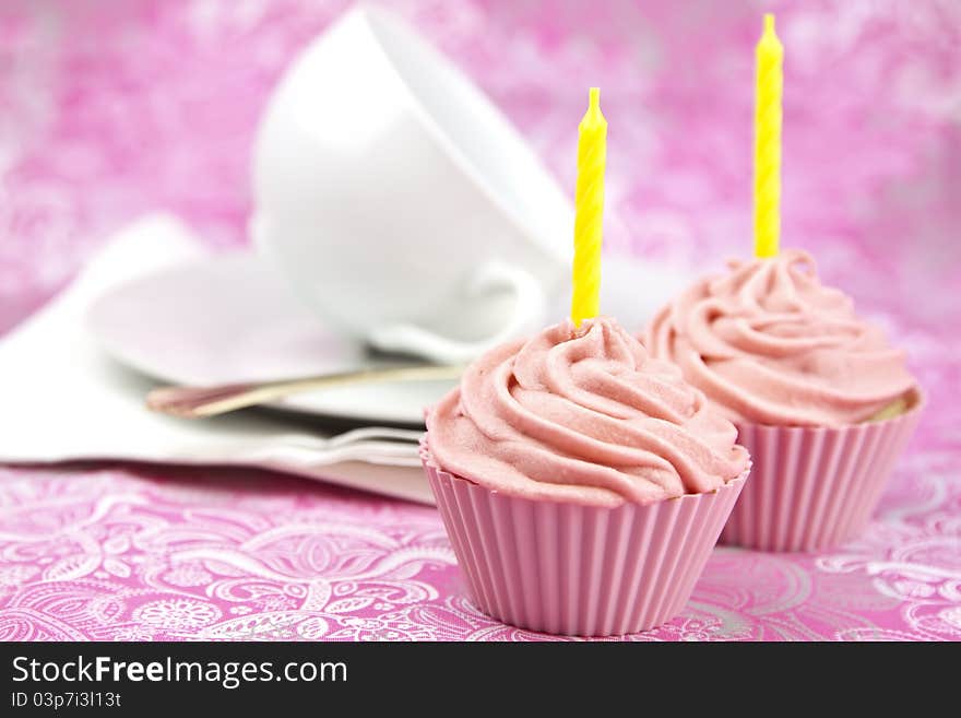 Pink cupcake with cream and candle on a pink background