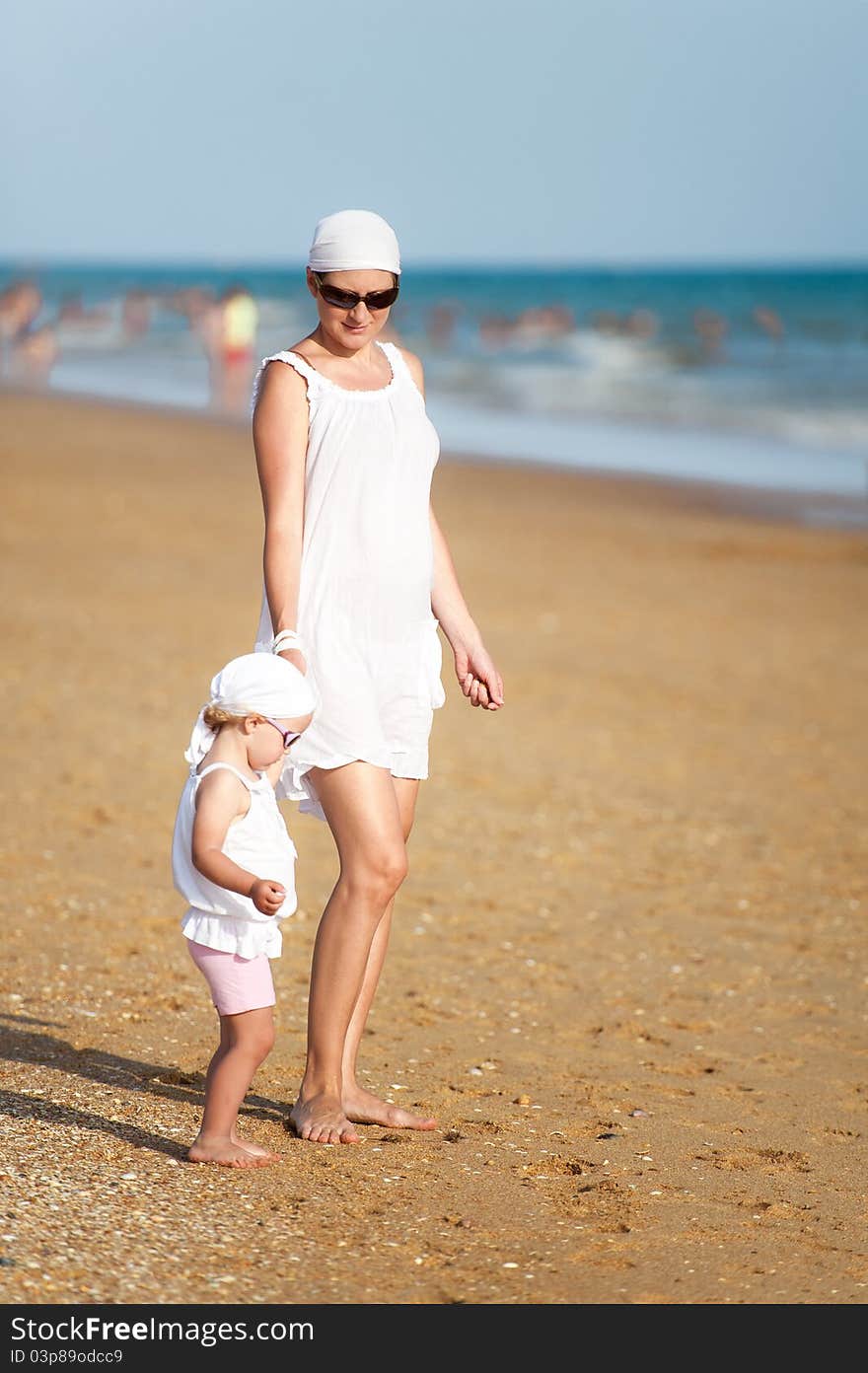 Mother with baby are walking on beach