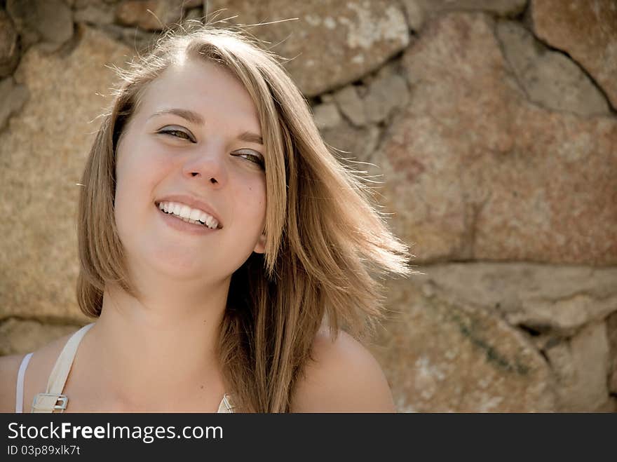 Teen girl happy smiling with background of wall made from natural stone. Teen girl happy smiling with background of wall made from natural stone