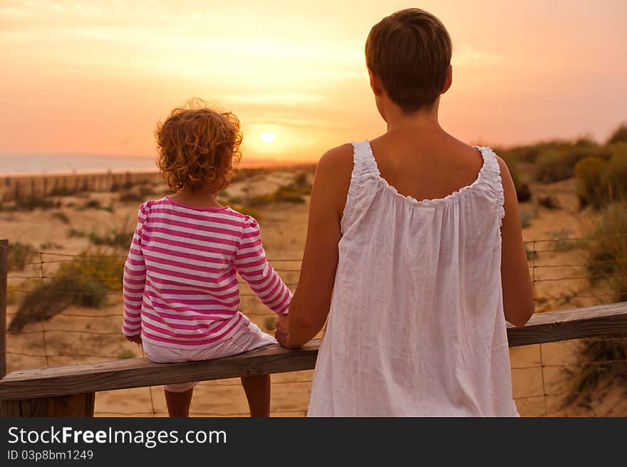 Mother and her baby are seating and looking sunset. Mother and her baby are seating and looking sunset