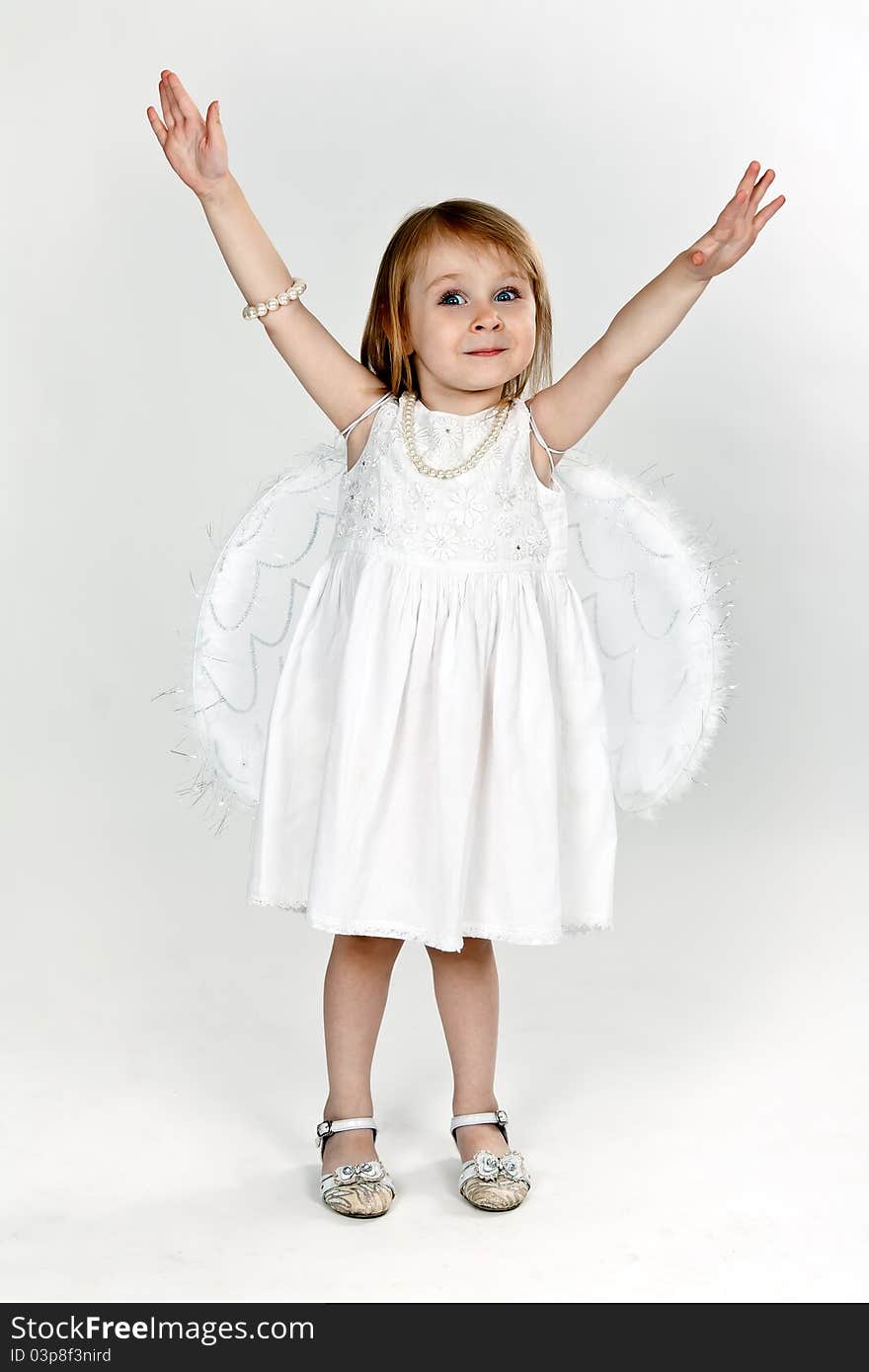 Little girl with angel wings in the studio on a gray background