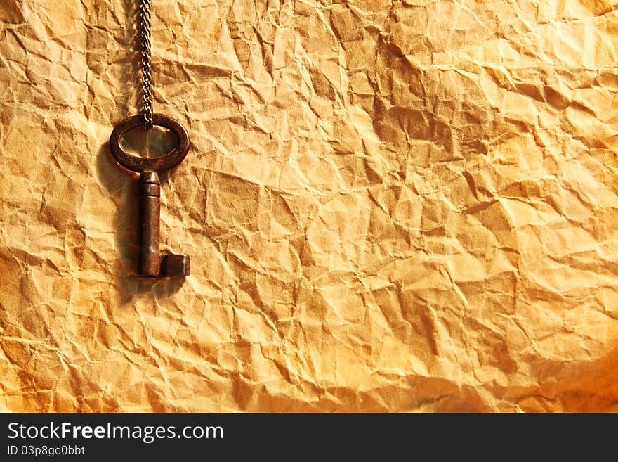 Blank sheet of crumpled paper and old key on chain. Blank sheet of crumpled paper and old key on chain